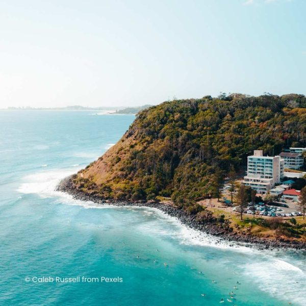 Apartment buildings set into a cliff edge next to green ocean